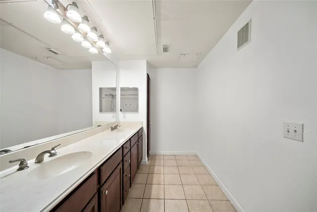 a spacious bathroom with a double vanity sink a vanity and a mirror