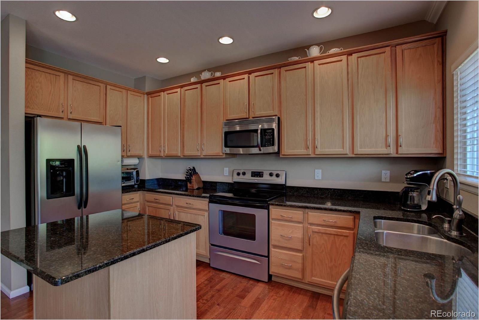 1021 Riddlewood Road Highlands Ranch, CO 80129 - Photo 3 of 29 a kitchen with kitchen island granite countertop a sink stove and refrigerator