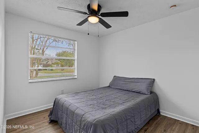 a view of an empty room with wooden floor a fireplace and a window