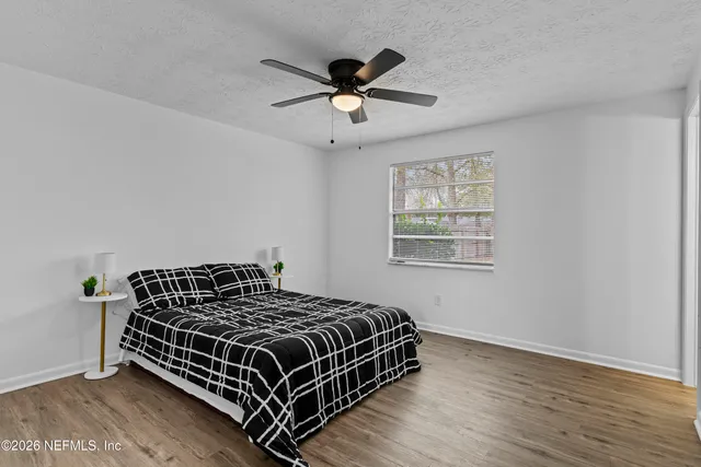 an empty room with wooden floor ceiling fan and windows