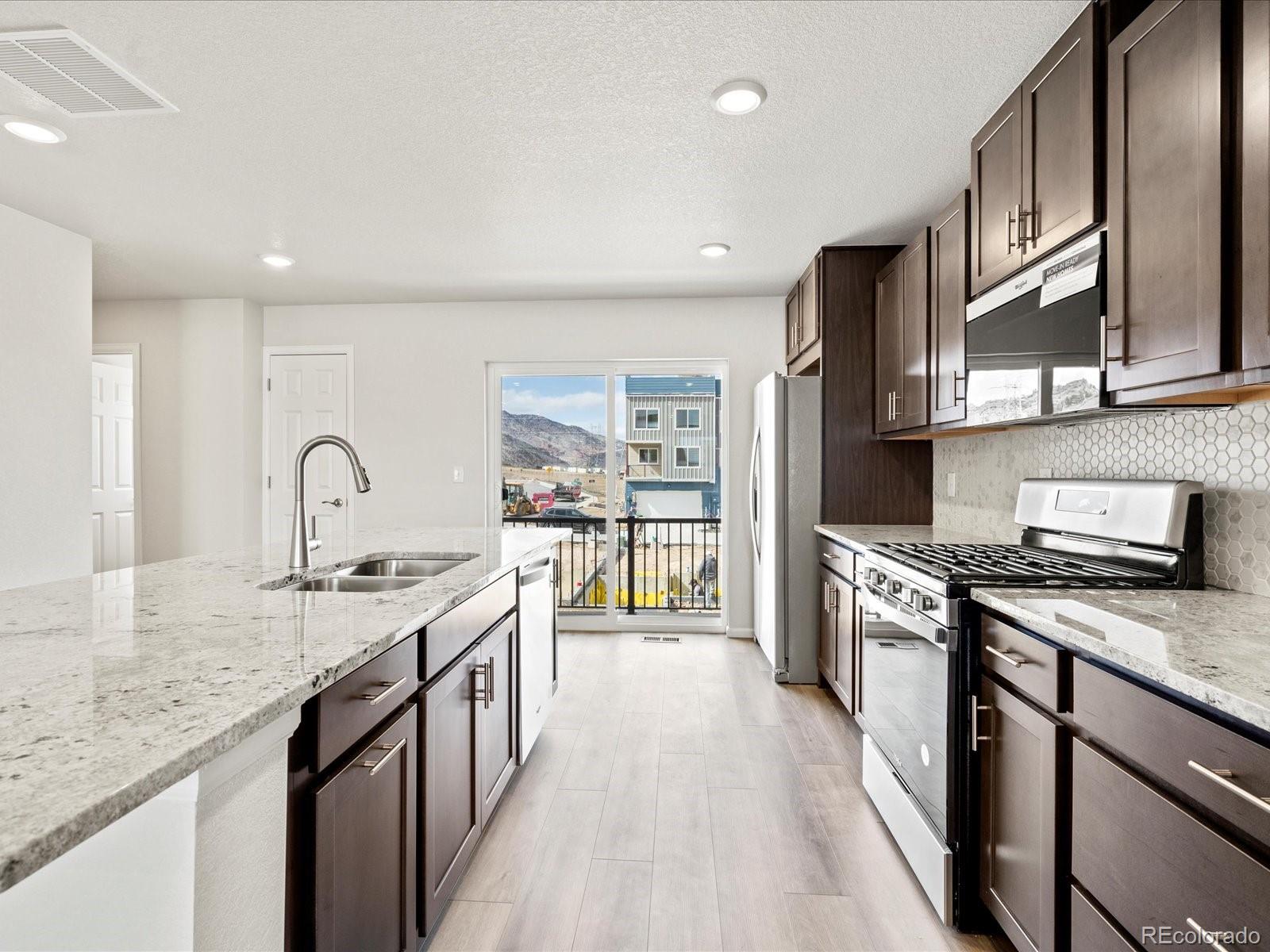 14412 Pansy Loop Morrison, CO 80465 - Photo 10 of 34 a large kitchen with stainless steel appliances granite countertop a lot of counter space and wooden floors