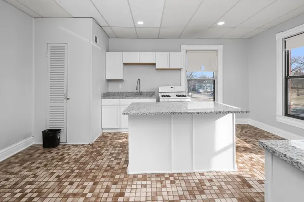 a kitchen with kitchen island granite countertop a sink stove and refrigerator