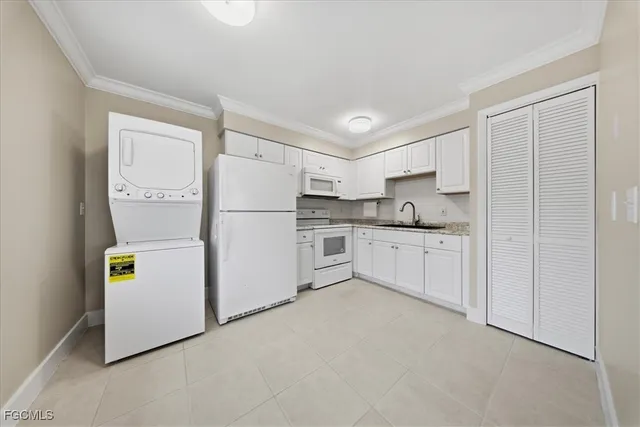 a kitchen with granite countertop a stove a sink and a white cabinets