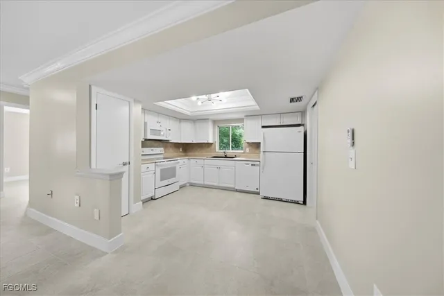 a view of a kitchen with white cabinets and refrigerator