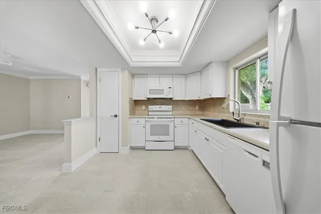 a large white kitchen with stainless steel appliances granite countertop a stove a sink dishwasher and a refrigerator with white cabinets