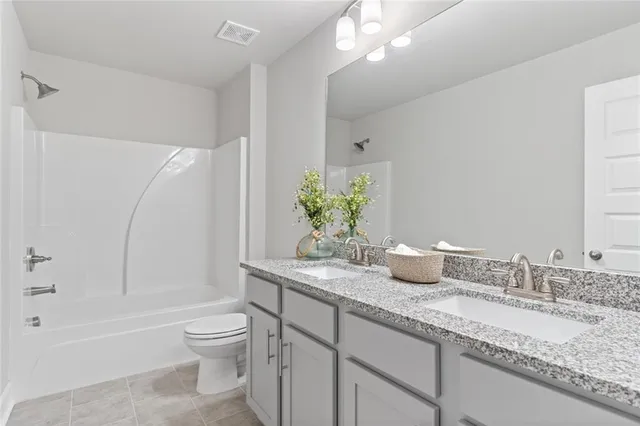 a bathroom with a granite countertop sink a toilet and bathtub