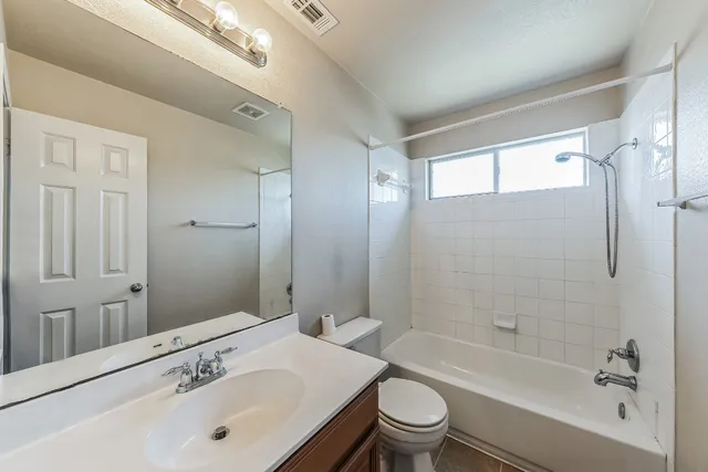 a bathroom with a bathtub shower sink vanity mirror and toilet