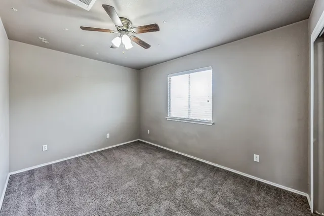 an empty room with windows and fan