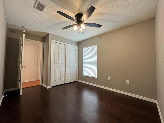 an empty room with wooden floor ceiling fan and windows