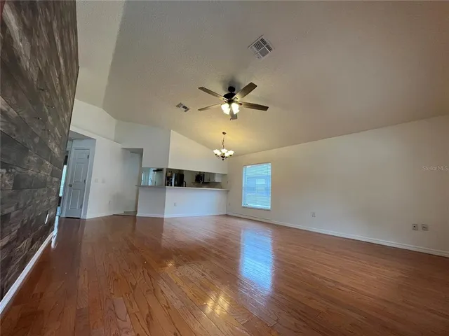 an empty room with wooden floor chandelier and entryway