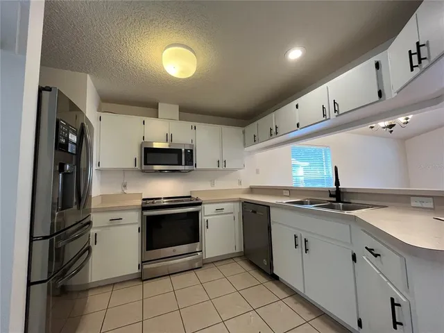 a kitchen that has a sink cabinets and stainless steel appliances