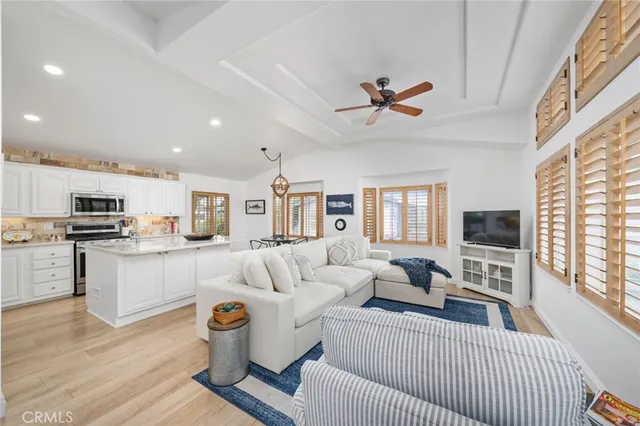 a living room with furniture a flat screen tv and kitchen view