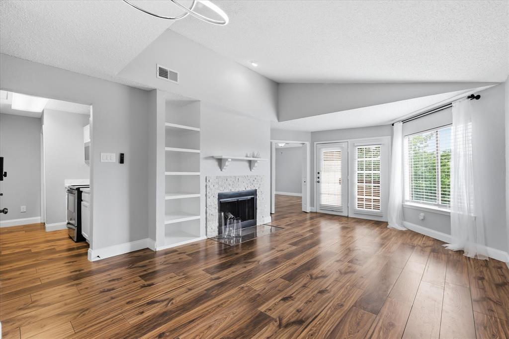 5550 Spring Valley Road, Unit A31 Dallas, TX 75254 - Photo 1 of 24 Spacious living area featuring wood-finish flooring, a fireplace with a mosaic tile surround, and built-in shelving