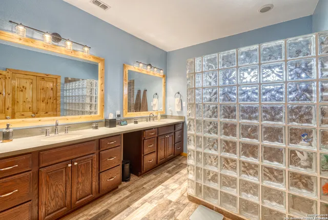 a spacious bathroom with a double vanity sink a mirror and a shower