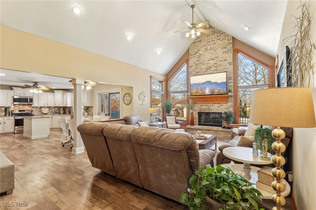 3353 Jens Way Perry, OH 44081 - Photo 9 of 49 Living room with light hardwood / wood-style flooring, ceiling fan, high vaulted ceiling, a brick fireplace, and ornate columns
