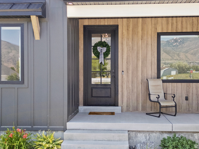 3111 South 1250 West Logan, UT 84321 - Photo 2 of 51 Modern exterior featuring a dark-paneled entry door with glass, a concrete porch, and a combination of vertical wood-finish siding and dark board-and-batten siding