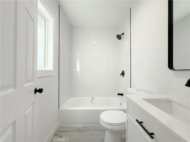 a bathroom with a bathtub shower sink vanity mirror and toilet