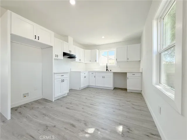 a kitchen with white cabinets and wooden floors