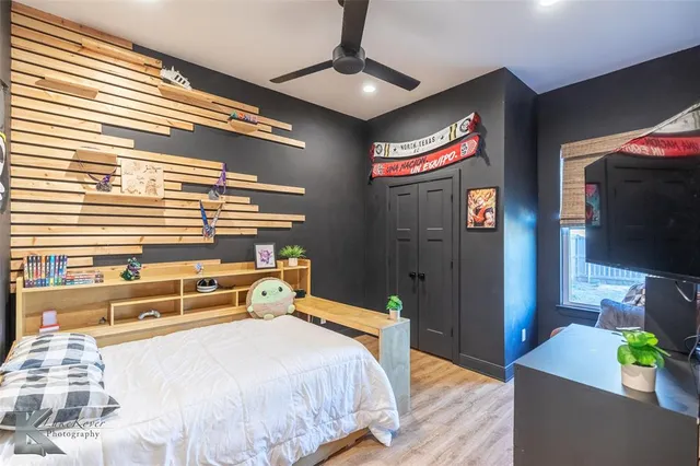 a bedroom with a bed and a flat tv screen on dresser