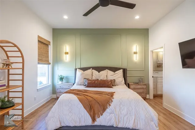 a bedroom with a large bed and a flat tv screen on dresser
