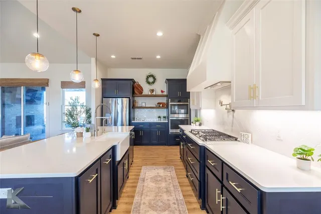 a kitchen with stainless steel appliances granite countertop a sink a stove and a wooden floors