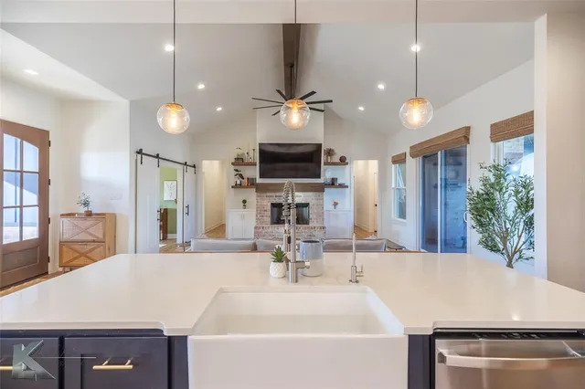 a large kitchen with kitchen island a sink stainless steel appliances and a chandelier