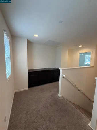 an empty room with a chandelier fan and windows