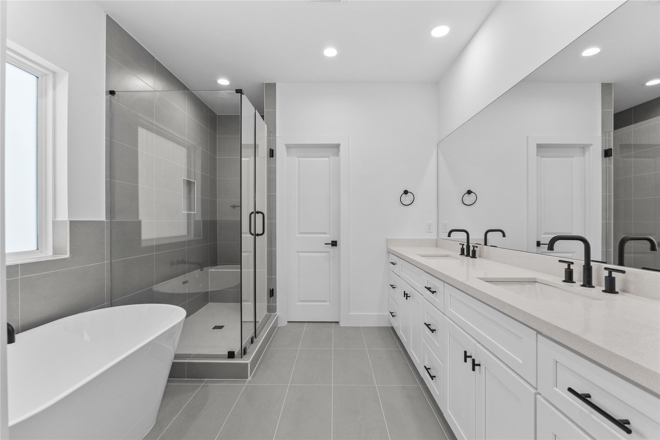3426 Bolin Road Houston, TX 77092 - Photo 22 of 34 Modern bathroom featuring a freestanding tub, glass-enclosed shower, double vanity with ample storage, and sleek fixtures. Bright and airy with neutral tones.