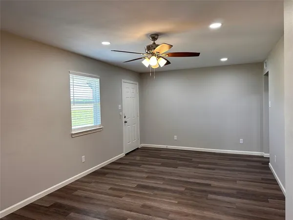 a view of an empty room with wooden floor and a window