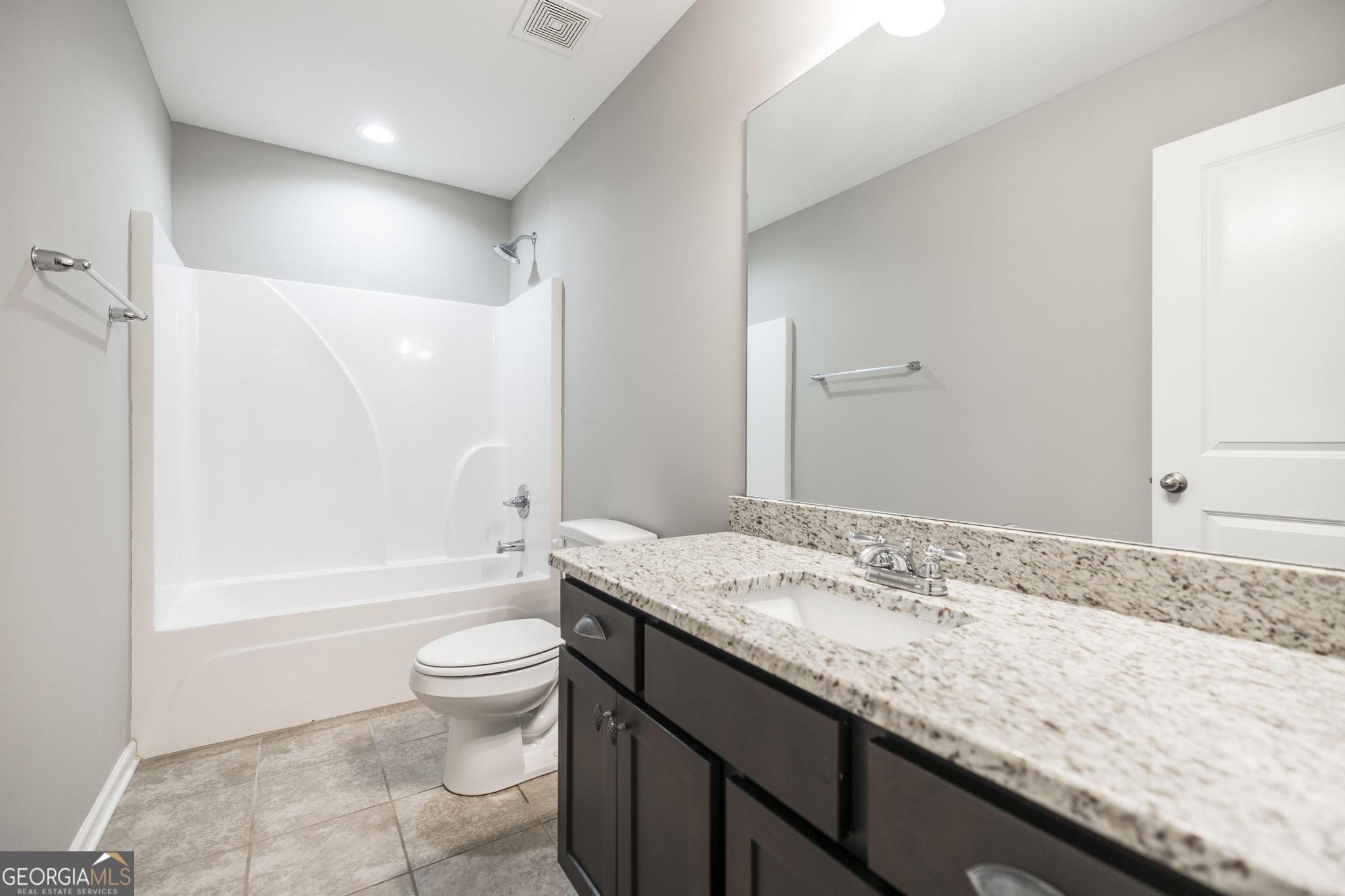 104 Goldenrod Trail Perry, GA 31069 - Photo 21 of 35 a bathroom with a granite countertop sink a toilet a mirror and bathtub
