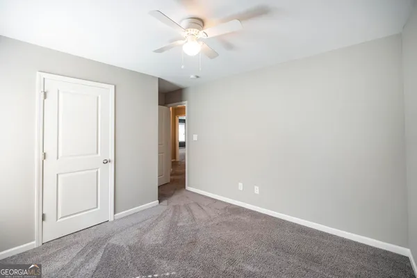 an empty room with closet and a ceiling fan