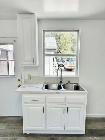 a kitchen with white cabinets and window