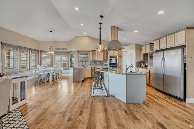 3054 West Ridgeline Road Stockton, UT 84071 - Photo 35 of 88 Kitchen with stainless steel appliances, light stone counters, a chandelier, island exhaust hood, and light wood finish cabinetry