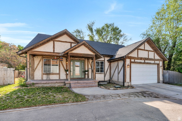 1727 South Sandhill Road Orem, UT 84058 - Photo 2 of 27 Tudor-style exterior featuring a prominent two-car garage, dark shingle roof, and a covered porch entry with exposed wood beams