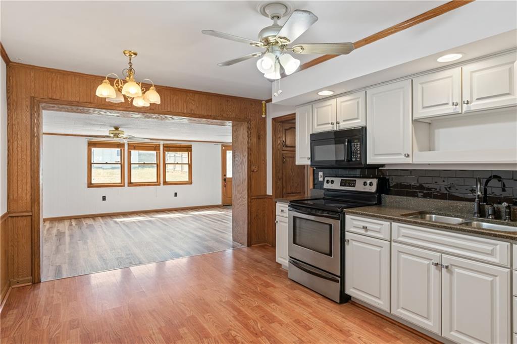 197 Douglass Road Beaver Falls, PA 15010 - Photo 13 of 33 a kitchen with stainless steel appliances granite countertop a stove top oven a sink dishwasher a dining table and chairs with wooden floor