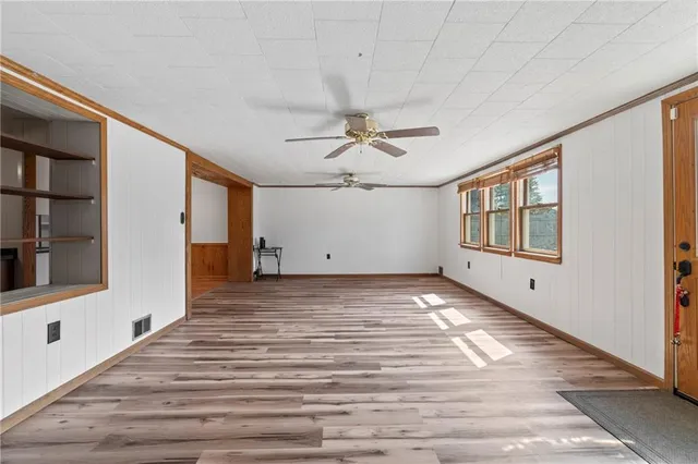a view of an empty room with window and wooden floor