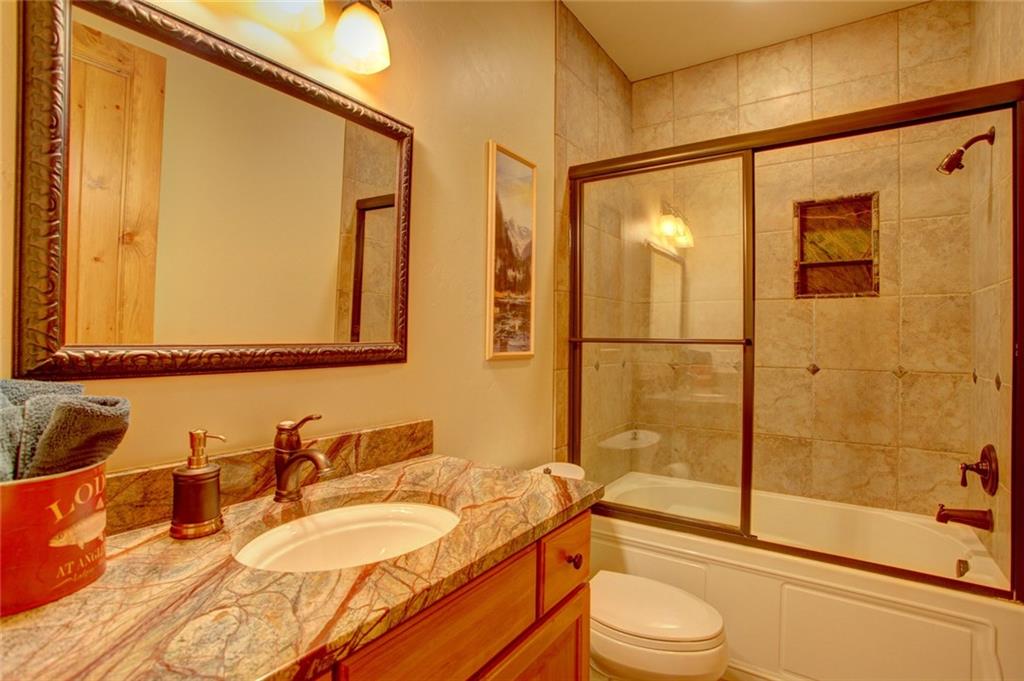 279 Two Cabins Drive Silverthorne, CO 80498 - Photo 16 of 30 a bathroom with a granite countertop sink toilet mirror and shower