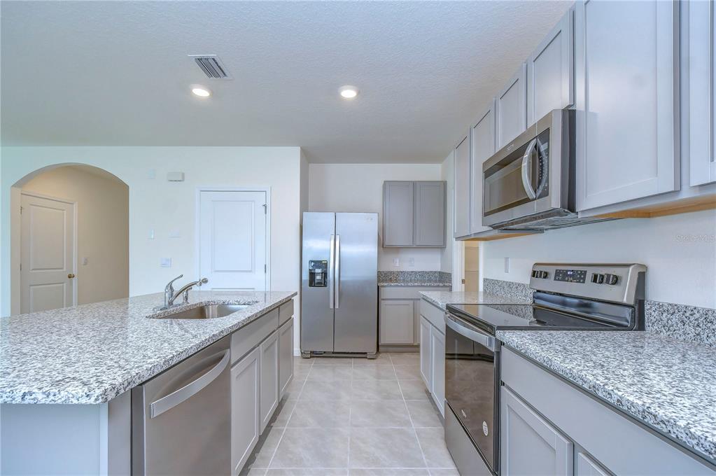 9176 Forge Breeze Loop Wesley Chapel, FL 33545 - Photo 8 of 33 a kitchen with stainless steel appliances granite countertop a sink stove and refrigerator