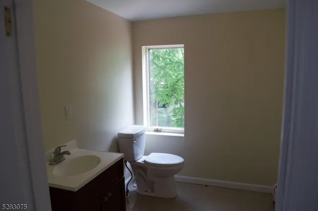 a bathroom with a sink toilet a mirror and window