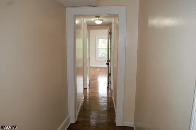 a view of a hallway with wooden floor and a door