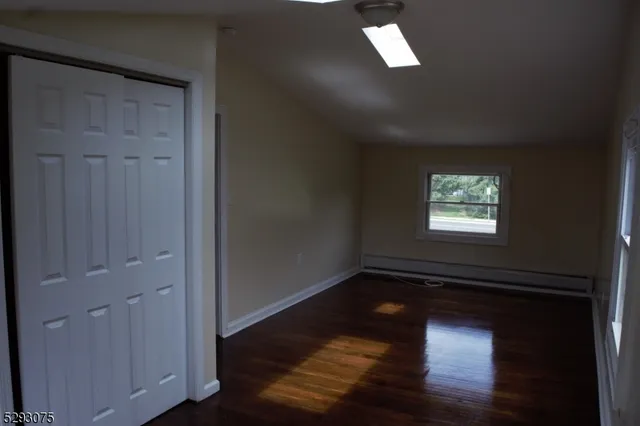 an empty room with wooden floor closet and windows