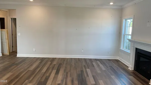 a view of an empty room with wooden floor and a fireplace