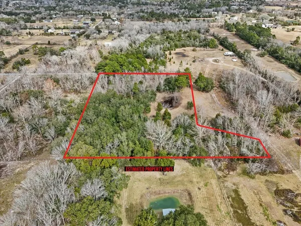 an aerial view of a house with a yard and large trees