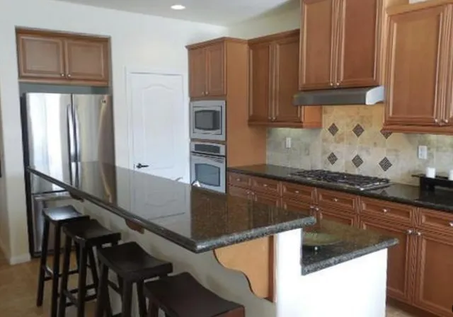 a kitchen with granite countertop a sink a stove and refrigerator