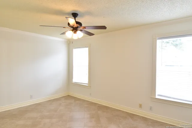an empty room with a window and a fan