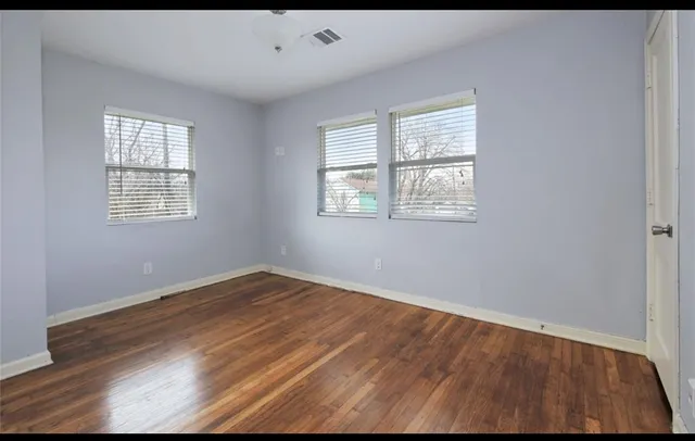 an empty room with wooden floor and windows