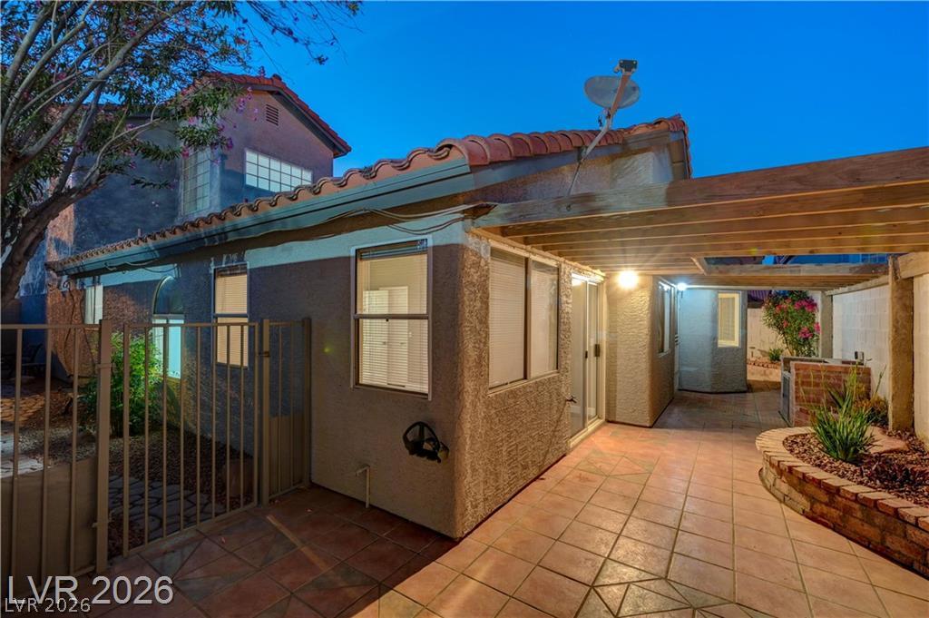 2283 Ramsgate Drive Henderson, NV 89074 - Photo 45 of 51 Tiled backyard patio features a wooden pergola and built-in masonry planter box against the stucco exterior.