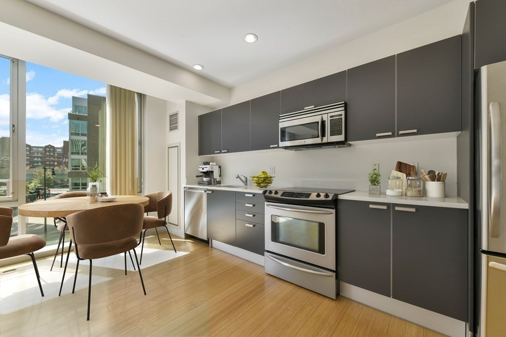 a kitchen with stainless steel appliances granite countertop a stove top oven a sink and a refrigerator