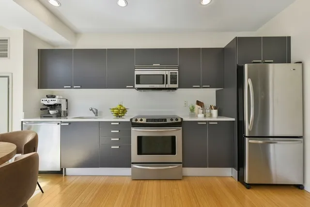 a kitchen with granite countertop a refrigerator and a stove top oven