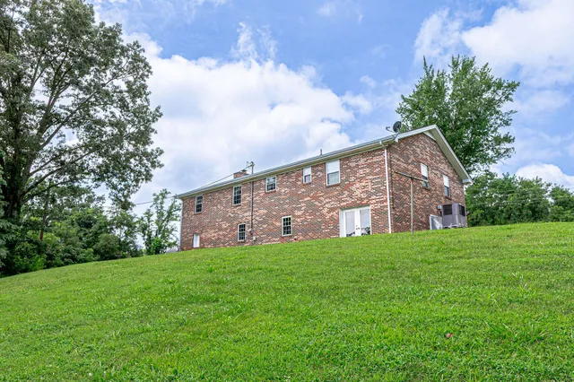 a view of a house with a big yard and large trees